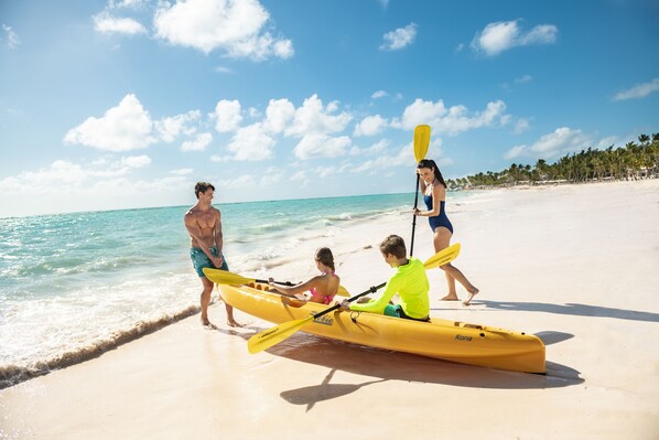 A group of people on a beach with a yellow kayak.