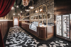 A restaurant with a patterned floor, a dessert display case, and a wine cooler.