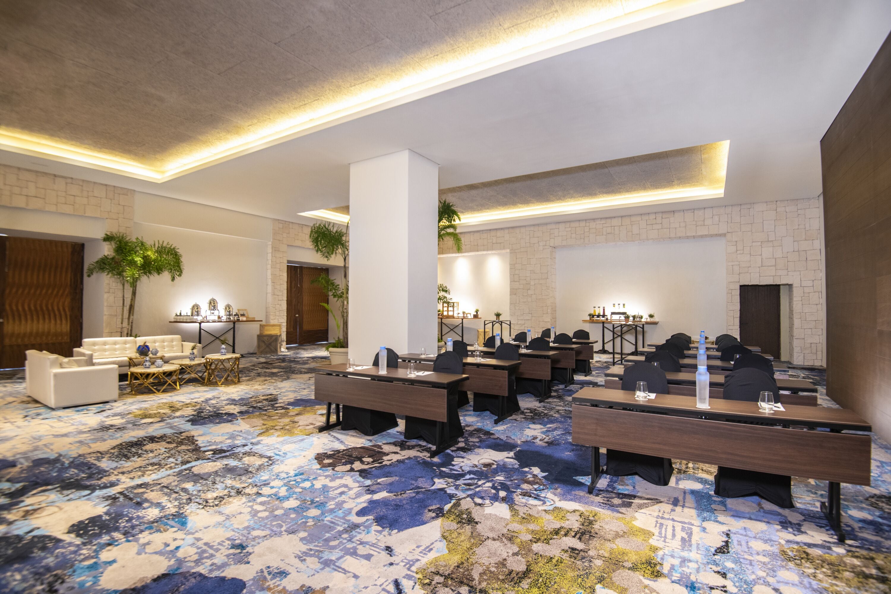 A conference room with a patterned carpet, white walls, and a stone accent wall.
