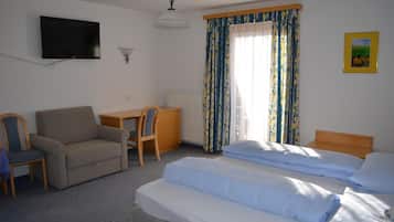 Een hotelkamer met een bed, een bureau, een stoel, een televisie en een raam met gordijnen.