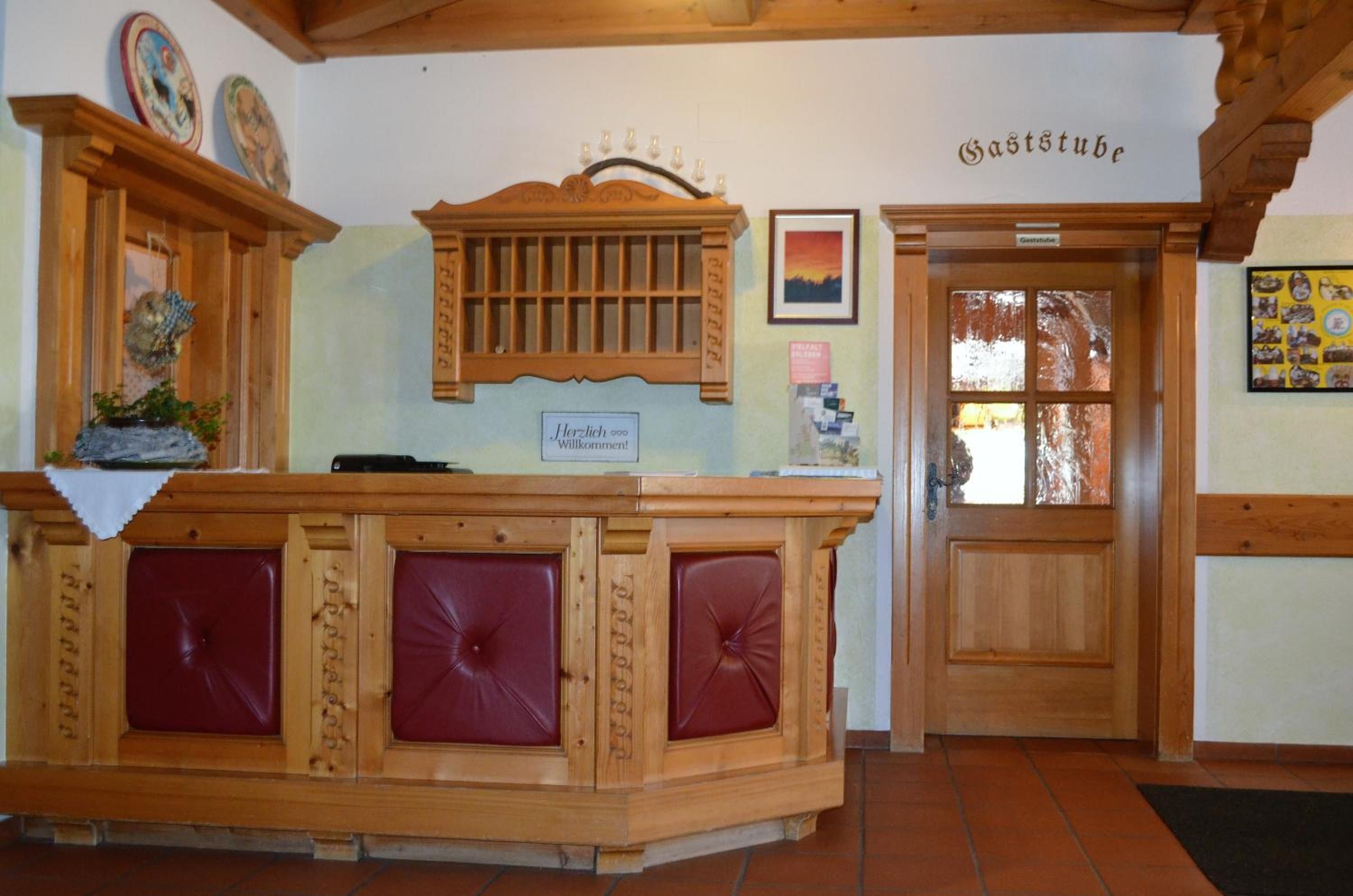 Una reception con piano in legno e sedute imbottite rosse.