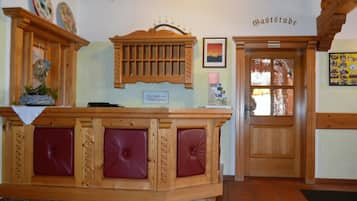 Una reception con piano in legno e sedute imbottite rosse.