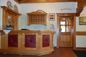A reception desk with a wooden finish and red cushioned seating.
