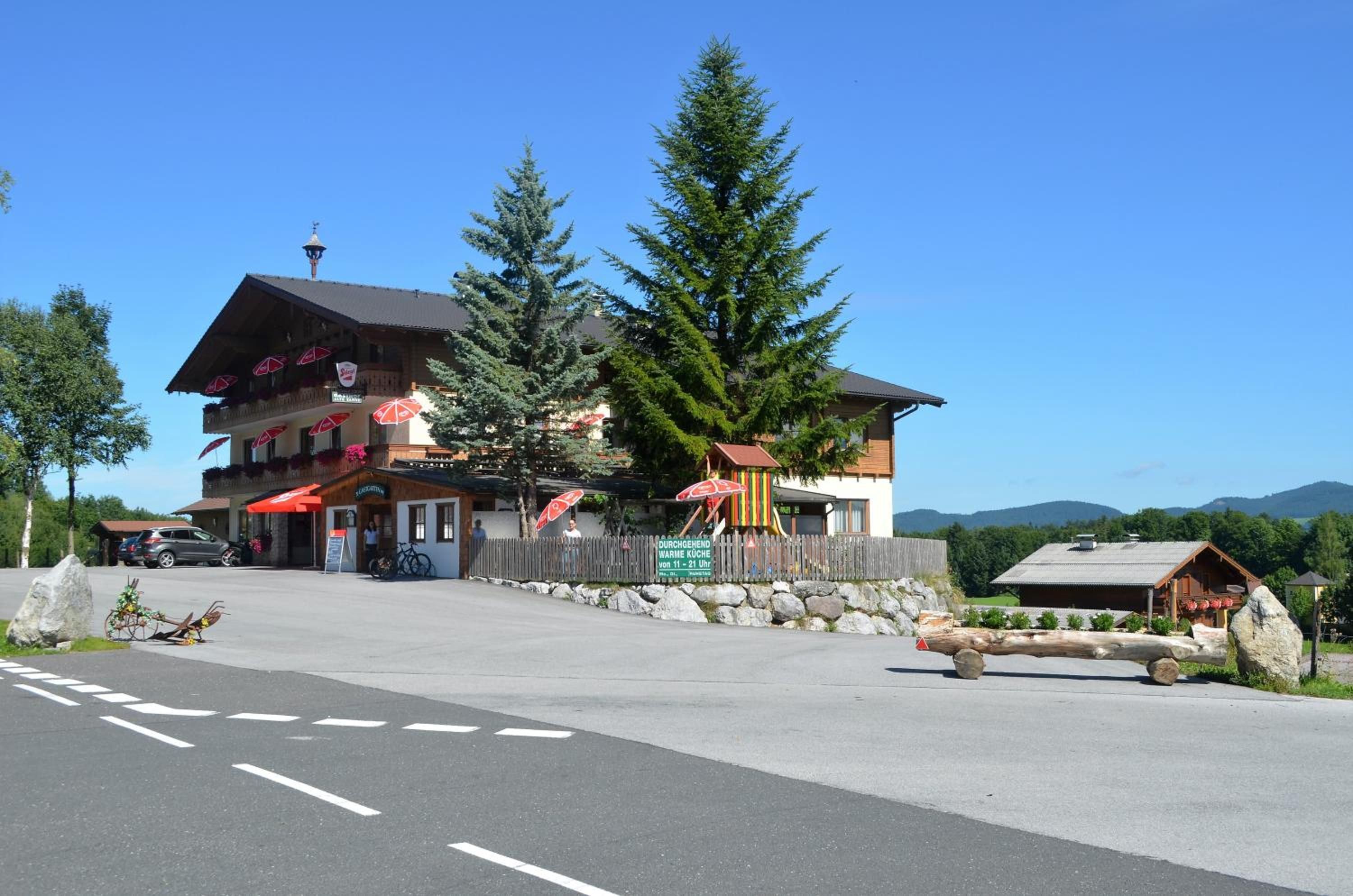 Een hotel met traditionele alpine architectuur, een parkeerplaats en uitzicht op het omliggende landschap.