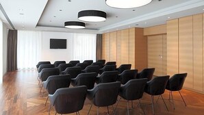 A conference room with rows of chairs, a flat-screen TV on the wall, wooden paneling, and recessed ceiling lights. - Hotel Otterbach (Bietigheim-Bissingen)