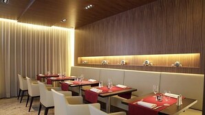 A hotel dining area with tables set for guests, a wooden wall with a lighted shelf, and a curtain backdrop. - Hotel Otterbach (Bietigheim-Bissingen)
