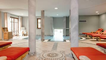 A spa area with red loungers, a pool, and a massage table.