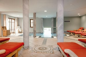 A spa area with red loungers, a pool, and a massage table.