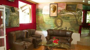 Une pièce comprenant deux canapés en cuir, une table basse en verre et une fresque représentant un lion sur le mur.