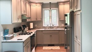 A kitchen with light wood cabinets, a central island, stainless steel appliances, and a window with a view.