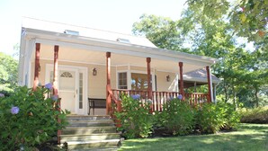 A two-story house with a porch, steps leading to the entrance, and a garden with hydrangeas.