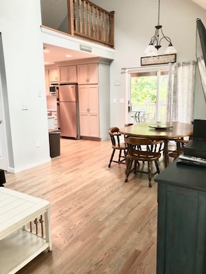A spacious kitchen with wooden cabinets and a built-in oven, leading to a dining area with a wooden table and chairs.
