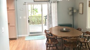 A spacious dining area with a wooden table and chairs, a chandelier, and a view of the outdoors through a sliding glass door.