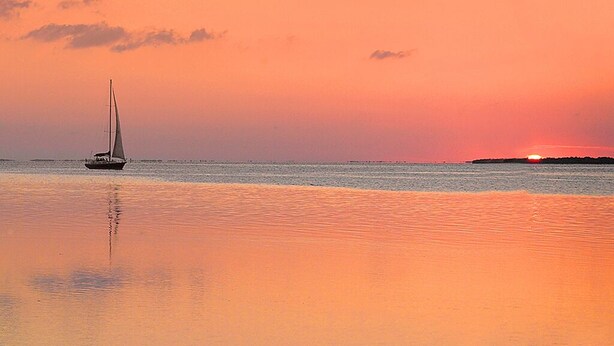 A sailboat on calm waters during sunset.