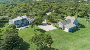 A large, two-story house with a spacious backyard, surrounded by dense greenery. - Nantucket Private Oasis - 6BR Pet-Friendly Home, Short Drive to Quidnet Beach (Nantucket)