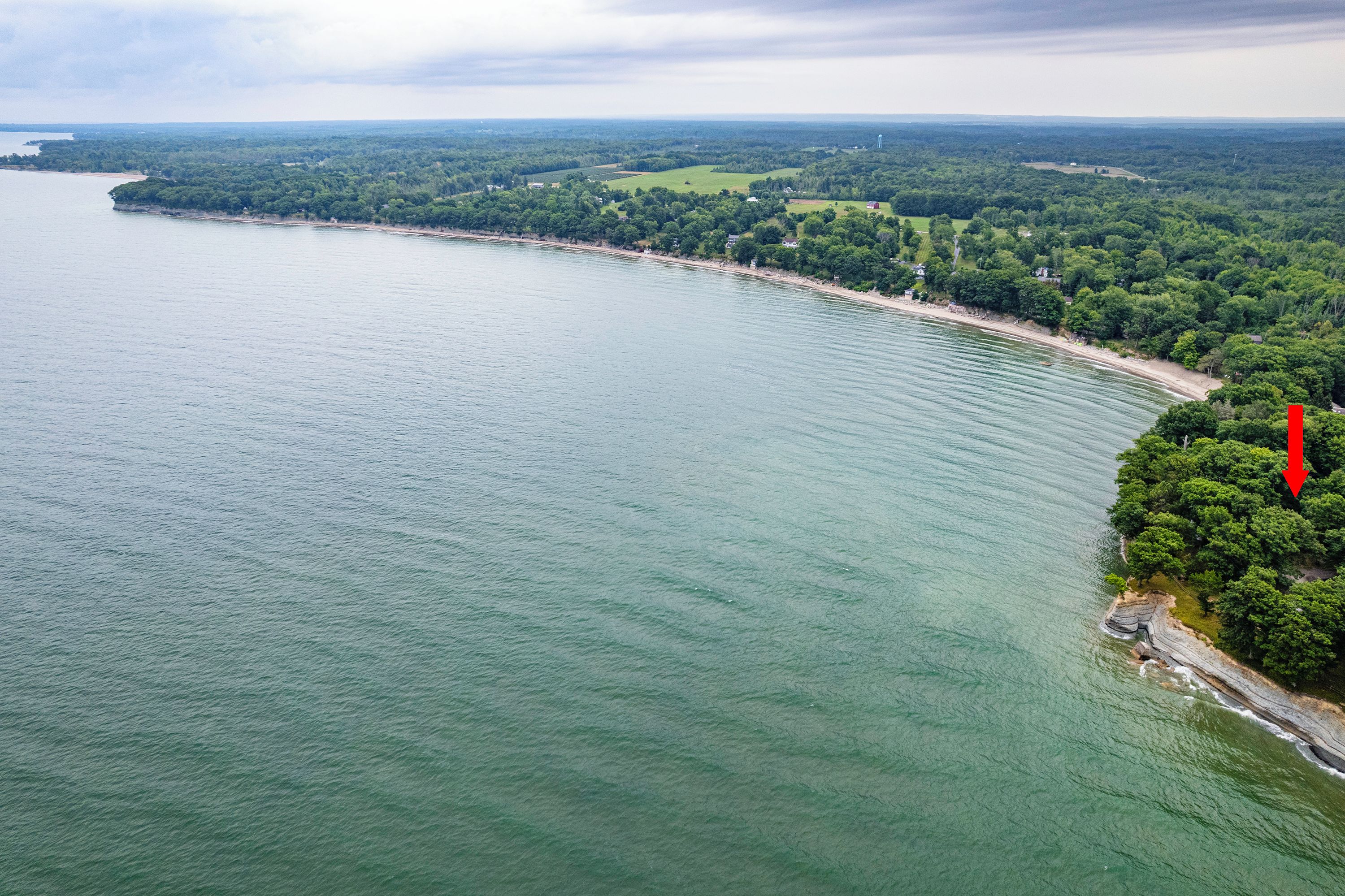 Eine Luftaufnahme einer Küstenregion mit einem weiten Sandstrand und dichter Vegetation.