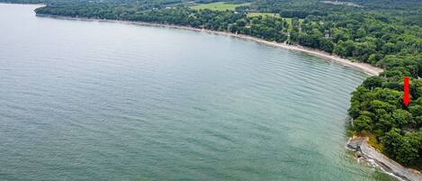 Eine Luftaufnahme einer Küstenregion mit einem weiten Sandstrand und dichter Vegetation.