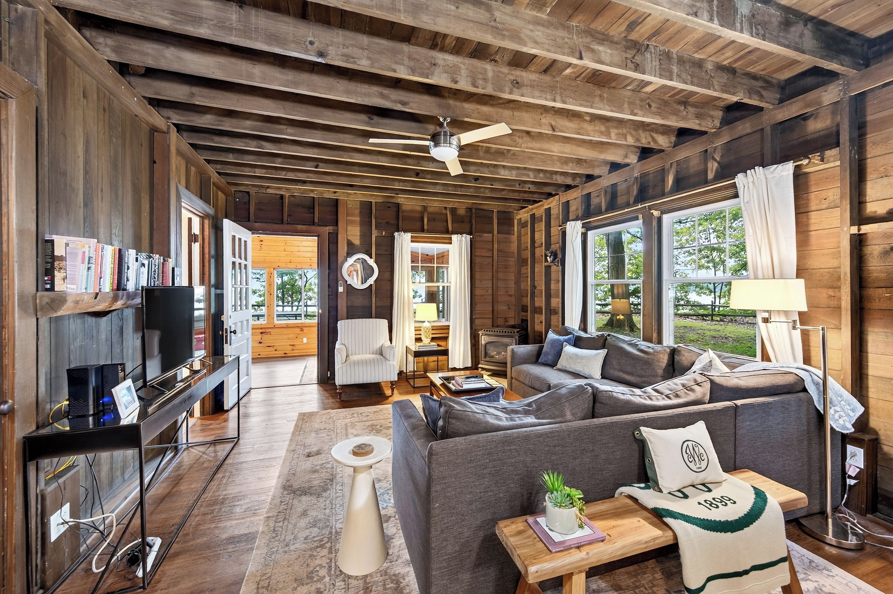 A cozy cabin interior with a sofa, a television, and a fireplace.