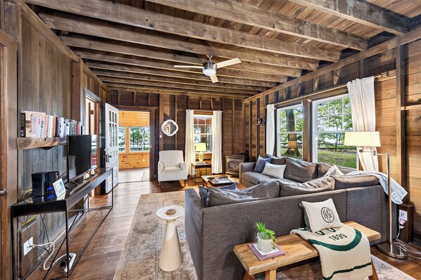 A cozy cabin interior with a sofa, a television, and a fireplace. - "The Richard" 3BR Lakefront: 60-Ac Estate Access with Private Beach sleeps 8 (Irving)