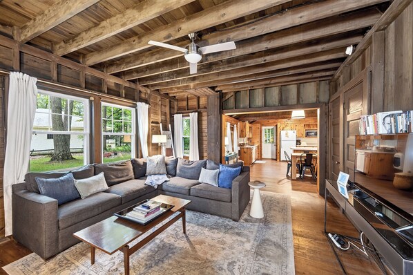 A spacious living room with a large sofa, a coffee table, and a ceiling fan.
