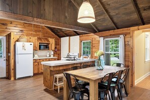 A wooden cabin interior with a kitchen, dining area, and large windows. - "The Richard" 3BR Lakefront: 60-Ac Estate Access with Private Beach sleeps 8 (Irving)