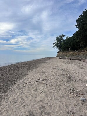 A beach with a pebbly shore, trees on the right, and a cloudy sky. - "The Richard" 3BR Lakefront: 60-Ac Estate Access with Private Beach sleeps 8 (Irving)
