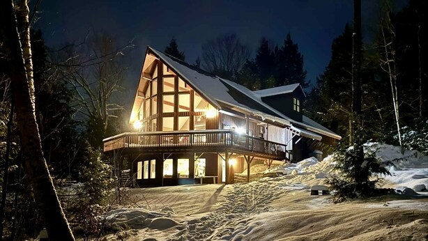 A large, multi-story lodge with a prominent balcony area, surrounded by snow-covered terrain and trees.