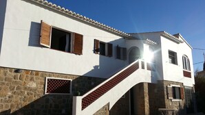 A white building with a stone base, a staircase, and multiple windows with shutters. - 5 DBR villa.Dual level with own pool. Walking distance to Calpe's Levante beach (Alicante)