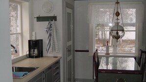 Una cocina con cafetera, lavabo y ventana con vistas a árboles.