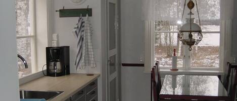 A kitchen with a coffee maker, a sink, and a window with a view of trees.