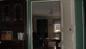 Una habitación con un armario de madera, un sillón de cuero negro, una mesa de madera y una puerta blanca.