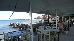 An outdoor restaurant with white tables and chairs, overlooking a rocky coastline and the sea. - Seaview Villa. Quiet and peaceful, relax and chill out (Lassithi)