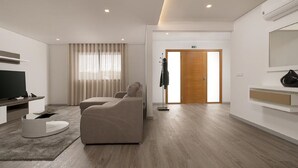 A modern living room with a sofa, a television, and a coat rack. - Villa Guinea - Fantastic House With Spectacular Views And Pool  (Funchal- Madeira)