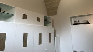 Ein Zimmer mit einer hohen, gewölbten Decke, weißen Wänden und integrierten Regaleinbauten.