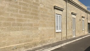 Ein Steinhaus mit drei Fenstern und einer Tür, das eine schlichte, schmucklose Fassade aufweist.
