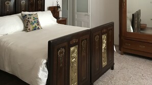 Ein Schlafzimmer mit Bett, Holz-Kopfteil, Schrank, Spiegel und einer Tür.