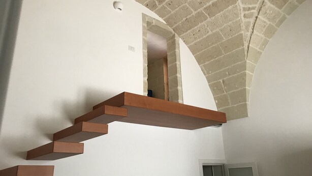 Ein modernes Interieur mit Ziegeldecke, weißen Wänden und einer Holztreppe mit integriertem Regal.