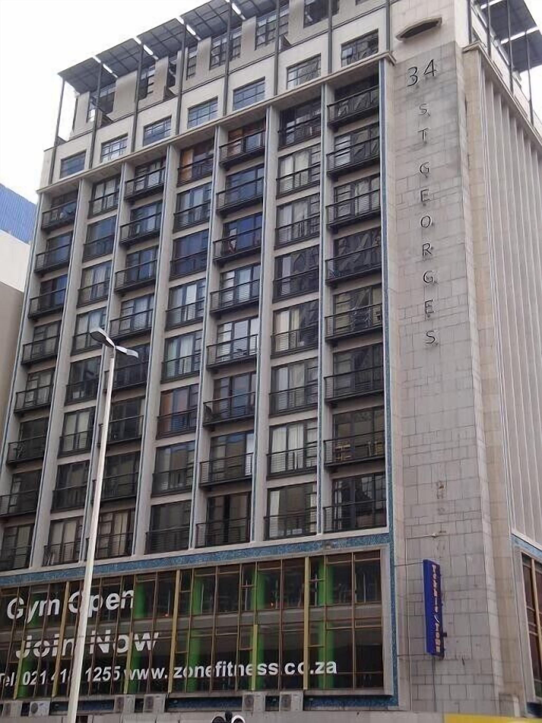 Een meerlaags gebouw met balkons en een bordje met daarop 'sportschool' onderaan.