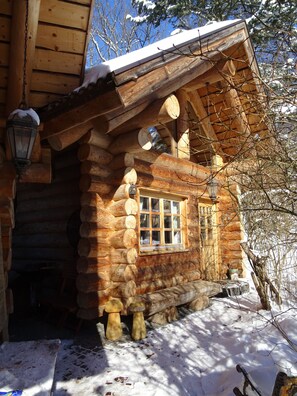 A log cabin with a wooden exterior, a window with a wooden frame, and a lantern hanging on the wall.