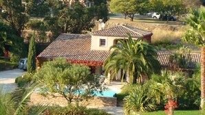 Une maison avec un toit en tuiles, une piscine et une végétation luxuriante.