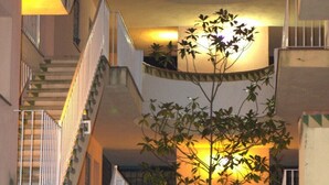 A multi-level building with a central staircase, a small tree, and a stone planter. - Apartment with terrace close to shops and the beach (Ampuriabrava)