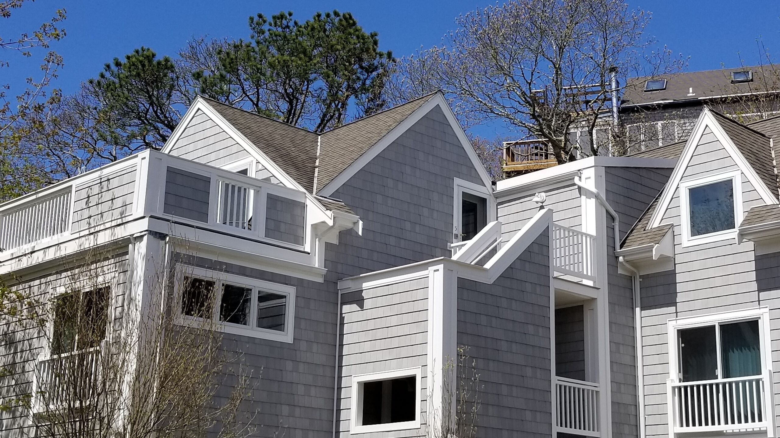 A multi-story residential building with a gabled roof, dormer windows, and a visible garage door.