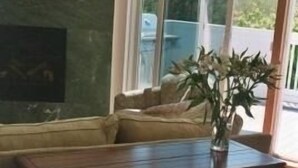 Una sala de estar moderna con una mesa de centro de madera, un sofá y un ventanal con vistas al exterior.