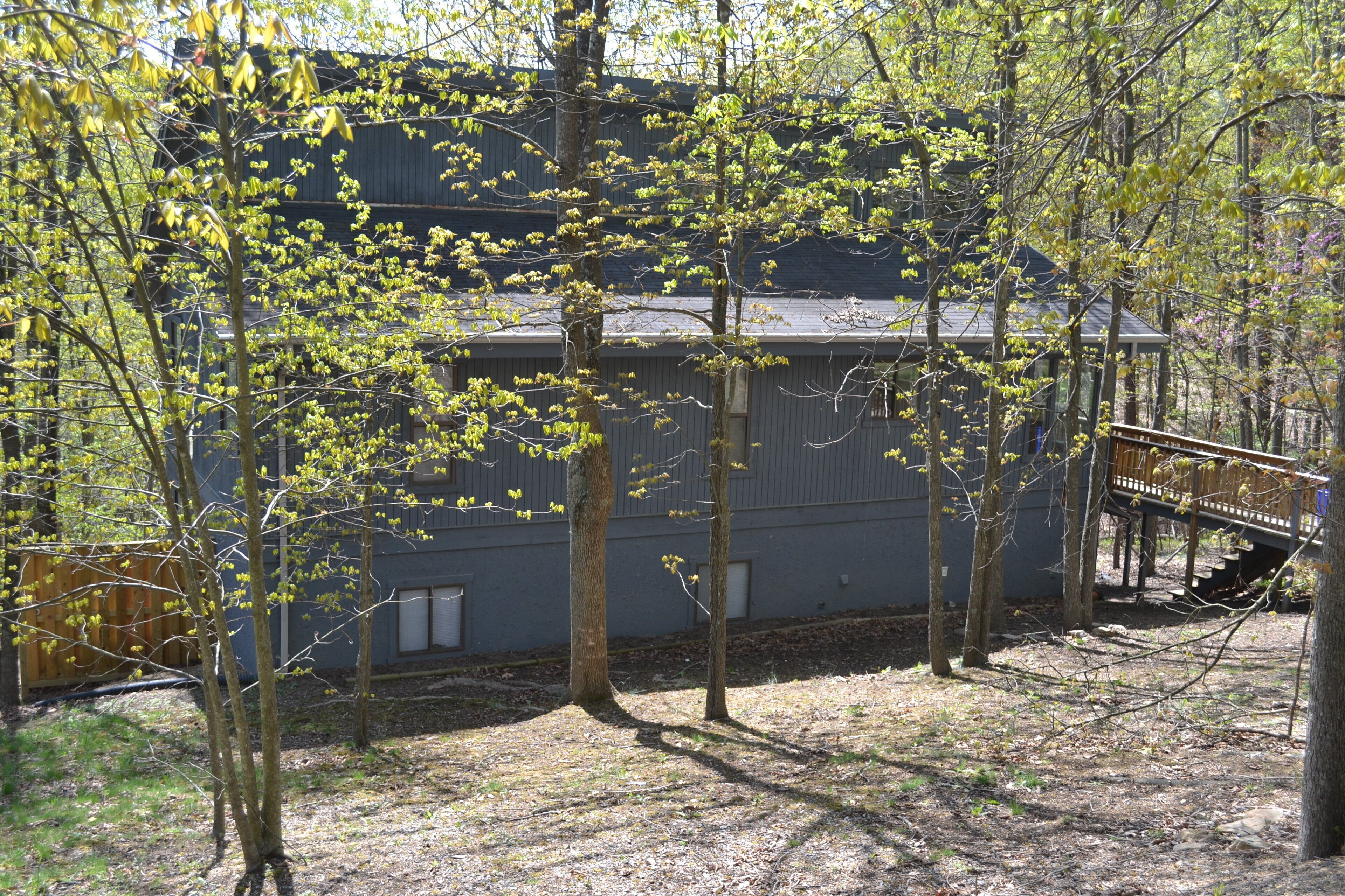 A two-story building with a wooden deck and a staircase leading to the upper level.
