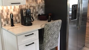 A kitchen with white cabinets, a stainless steel refrigerator, a coffee maker, and a patterned chair. - Super close to campus and Lloyd Noble Center. Clean home with updated kitchen. (Norman)