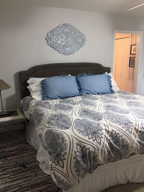 A bedroom with a bed, a bedside table, a lamp, and a decorative wall piece. - Super close to campus and Lloyd Noble Center. Clean home with updated kitchen. (Norman)