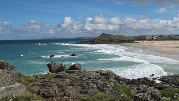 A coastal landscape with rocky terrain, a sandy beach, and a hill with ruins. -  Peaceful with Patio in Downalong, Moments from Beaches, Harbour, Town, Parking (St Ives)