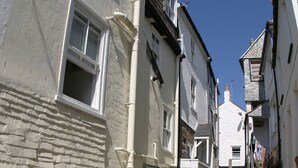 A narrow cobblestone street flanked by white buildings with multiple windows and a small step leading to a higher level. -  Peaceful with Patio in Downalong, Moments from Beaches, Harbour, Town, Parking (St Ives)