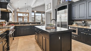 Una cocina moderna con armarios oscuros, electrodomésticos de acero inoxidable y una isla grande.