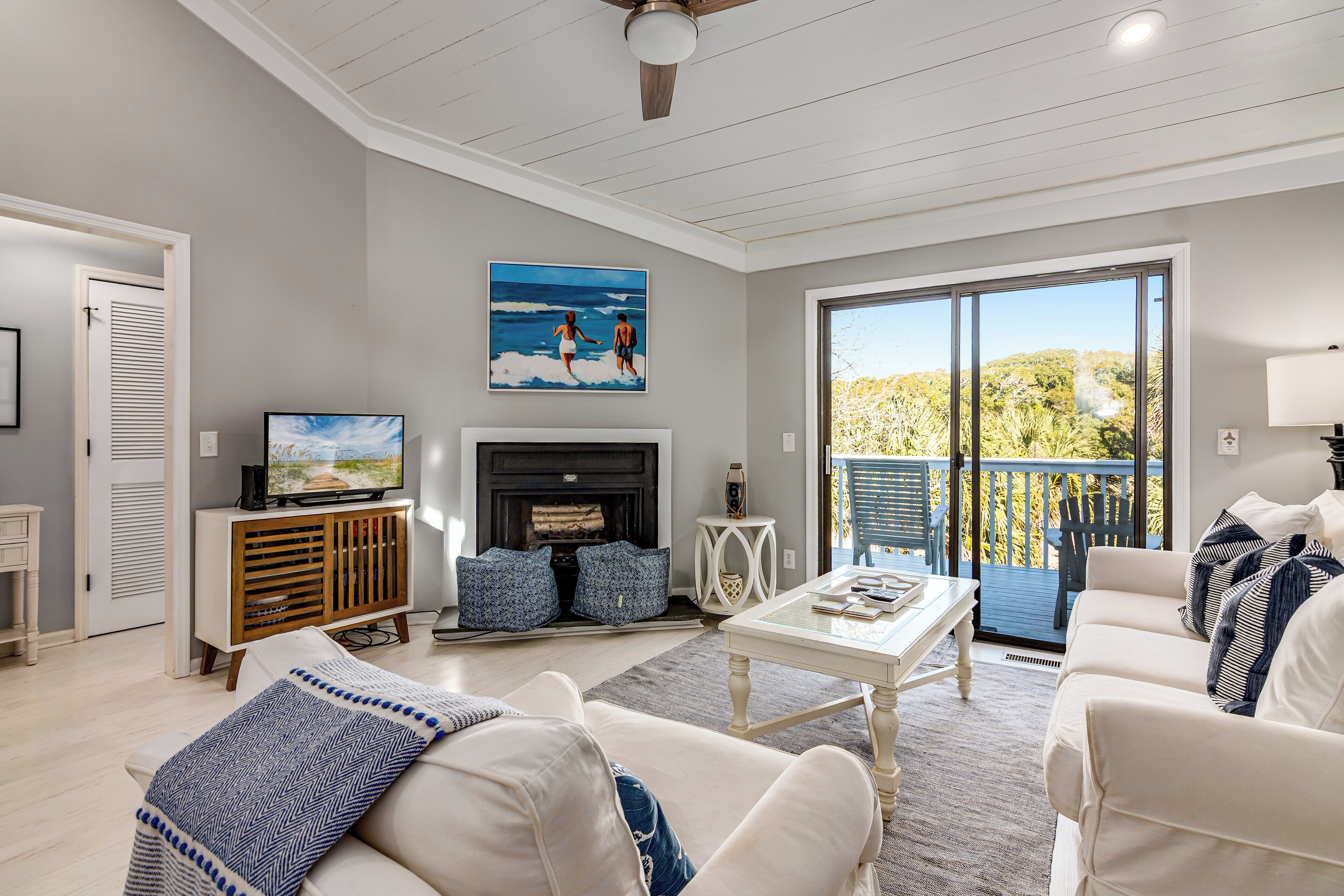 A living room with a fireplace, a television, and a balcony with a view of the outdoors.